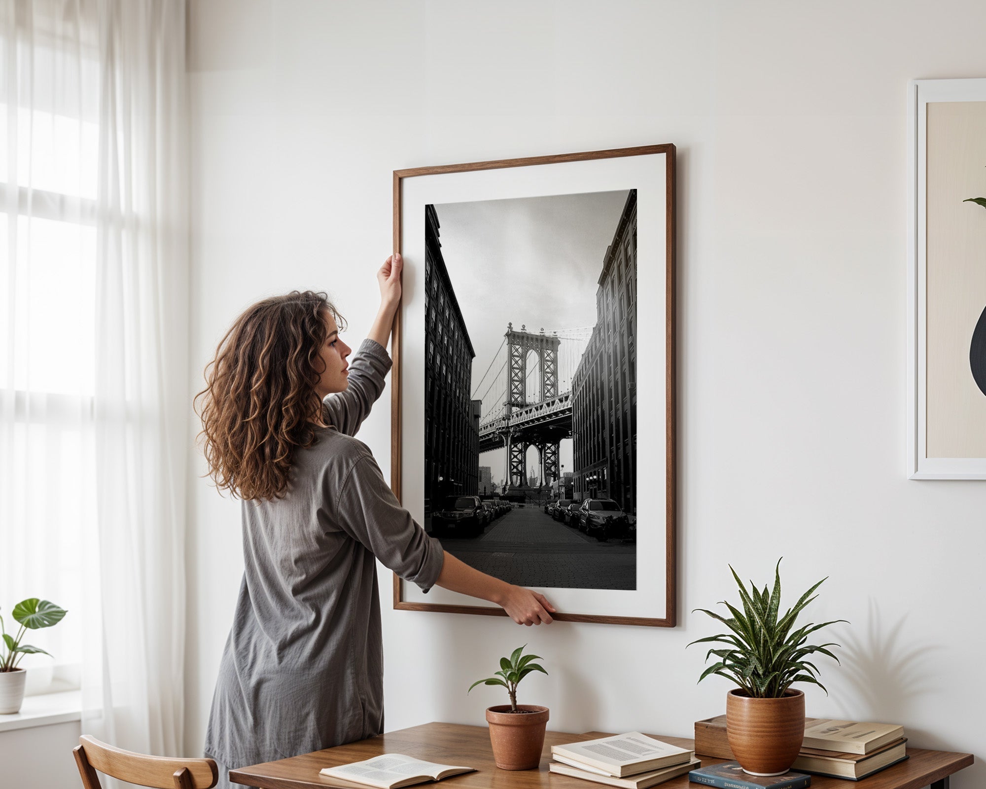 Framed picture being hung on wall with level tool and hammer